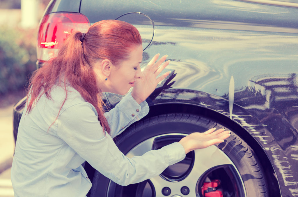 woman frustrated with a dent on her car's back side