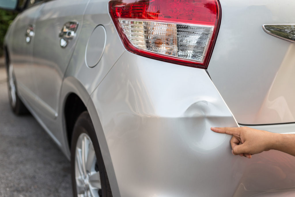 silver car with a small back bumper dent