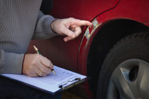 close up insurance adjuster examining a car for dent repair