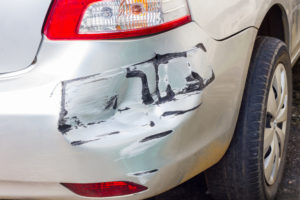 close up of a dent on a white car's back bumper