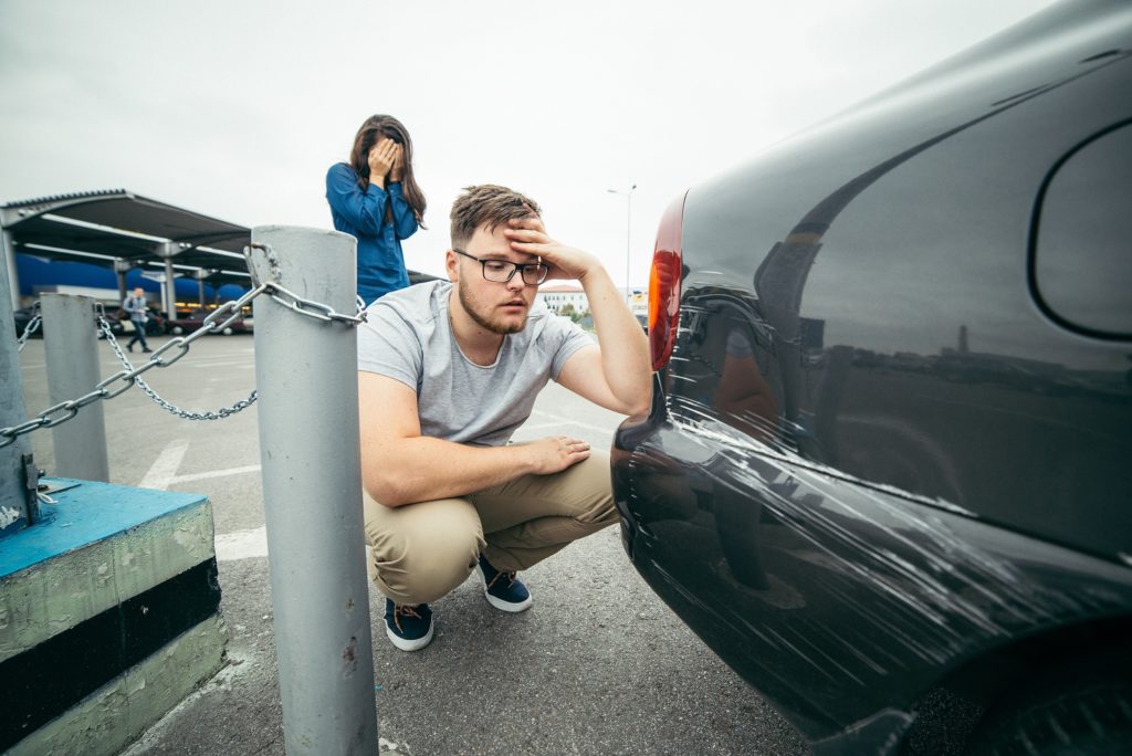 man surveying a new car dent on his car who needs affordable dent repair