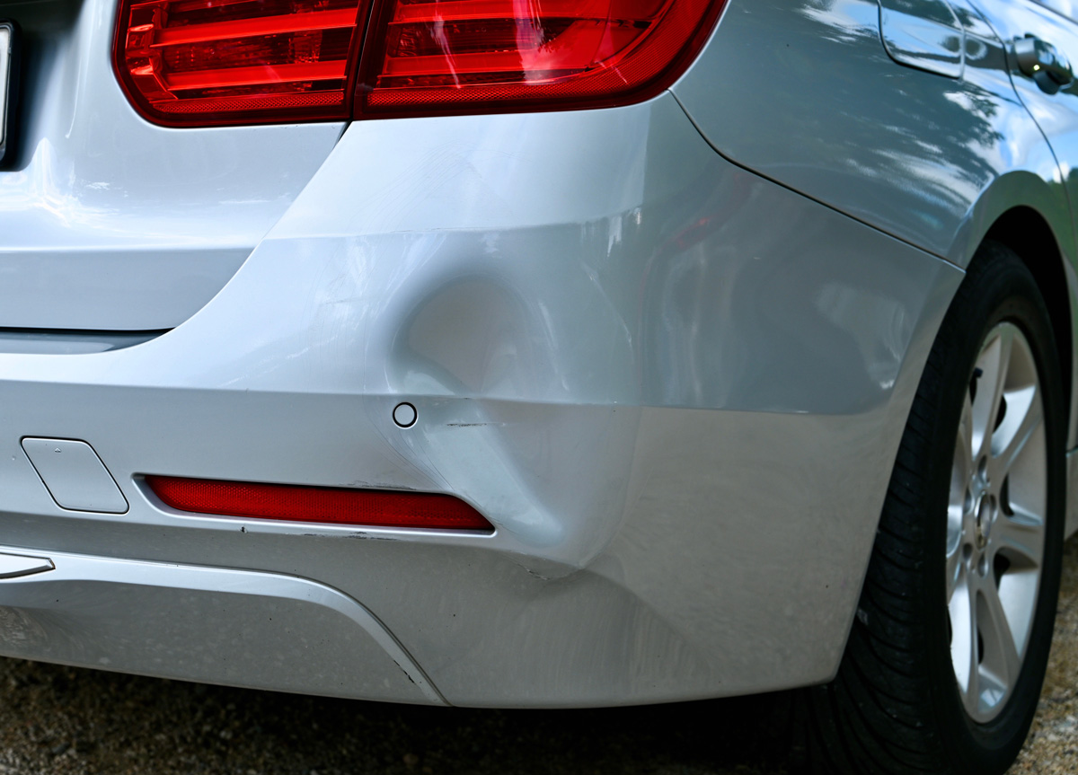 A dent on the back of a silver car in El Paso.